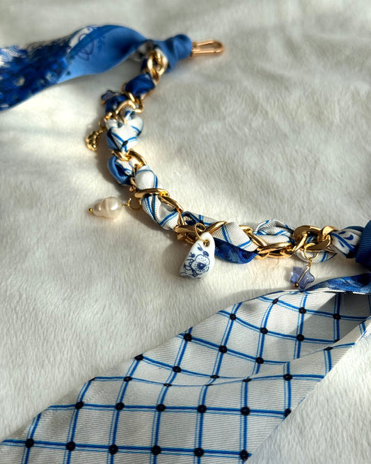 Bag charm with blue and white patterned fabric and gold chain on a white background